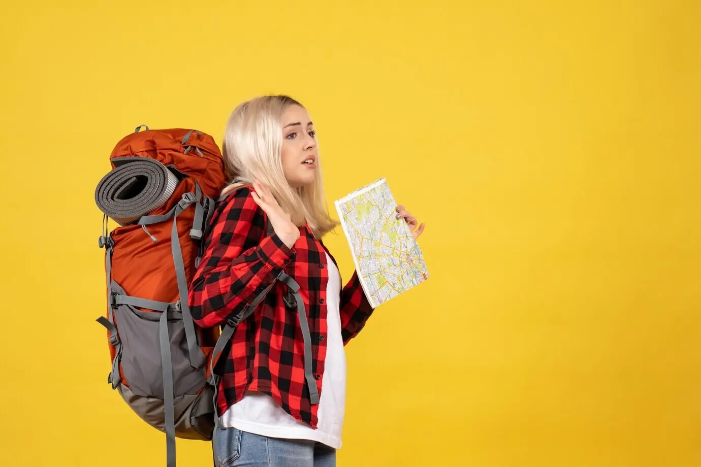 Vorderansicht eines besorgten blonden Mädchens mit ihrem Rucksack, das eine Karte hält.